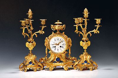 Pendule mit zwei Kerzenleuchtern, Frankreich, um 1900, verzierte Bronze mit alter Vergoldung, matt und glänzend, seitliche Widderköpfe mit ...