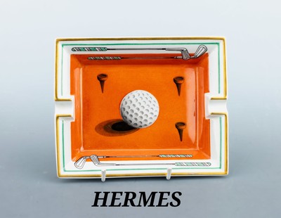 HERMES Aschenbecher "Golfball", Porzellan, weißer Grund goldfarb. Rand, Malerei mit Golfball auf orangefarb. Hintergrund, weitere ...