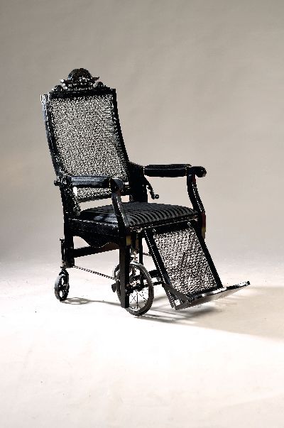 Krankenstuhl, deutsch, um 1890/1900, Nussbaum, neu schwarz gefaßt, orig. Mechanik zum Einstellen der Rückenlehne und des Fußschemels auf Rädern, ...