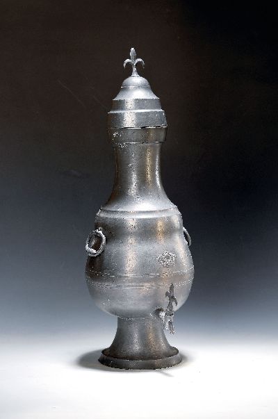 Dröppelminna, deutsch, Mitte/ausgehendes 18.Jh., Zinn, frontseitig abgebildete Krone, Deckelaufsatz Fleur de lis, H. 58 cm