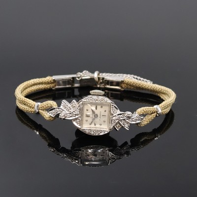 TRADITION Diamantbesetze Damenarmbanduhr in WG 585/000, USA/Schweiz um 1950, Handaufzug, 2-tlg. Geh., Boden aufgedr., floral geformte Anstöße f. ...