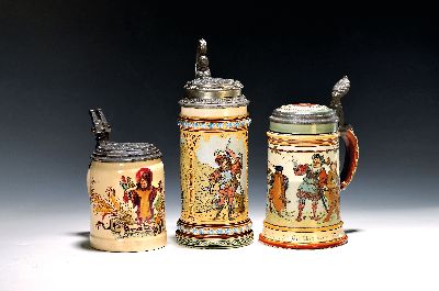Drei Mettlach-Krüge, Villeroy & Boch, um 1900, Feinsteinzeug, a. 2003 mit Zinndeckel, geritzter Dekor, H. ca. 25.5 cm, Deckel bez. und dat. 1892; b. ...