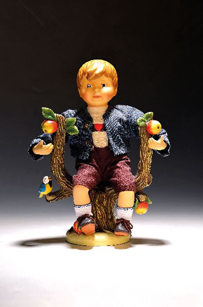 Große Porzellanpuppe "Herbst", M.J. Hummel, 1997, Körper und Sockel aus Porzellan, textile Bekleidung, auf Apfelbaum sitzender Knabe als ...