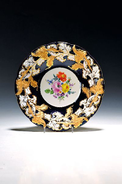 Prunkschale, Meissen, 1970er Jahre, 2. Wahl, reliefiert, matt- und glanzvergoldet, partiell kobaltblau glasiert, mittig bunte Blumen, D. ca. 25.5cm