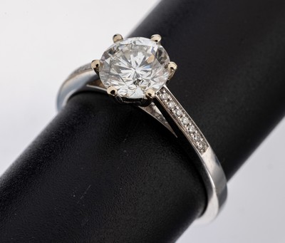 18 kt Gold Brillant-Ring, WG 750/000, mittig Brillant ca. 1.36 ct l.get.Weiß/p, Ringschultern mit 14 Brillanten zus. ca. 0.06 ct (grav.) Weiß/si, ...