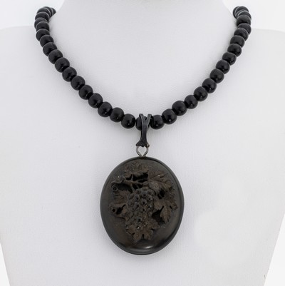 Medaillon-Anhänger, um 1890, Jet, ovale Grundform, Deckel mit plastischem Weinlaubdekor, aufklappbar, innen grav. mit Darstellungen von Vögeln, ...
