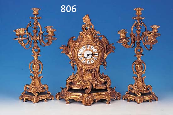 DEKORATIVE KAMINUHR MIT 2 KERZENLEUCHTERBEI- STELLERN, FRANKREICH, UM 1860, REICH VER- ZIERTER UND VERGOLDETER BRONZEGUß IM ROKOKO- STIL MIT ...