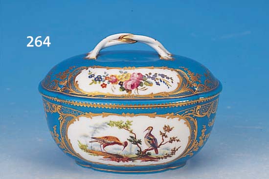Ovale Dekeldose, Sèvres, um 1790, Weich- porzellan blau glasiert und mit Golddekor, in Kartuschen feine bunte Malerei von exoti- schen ...