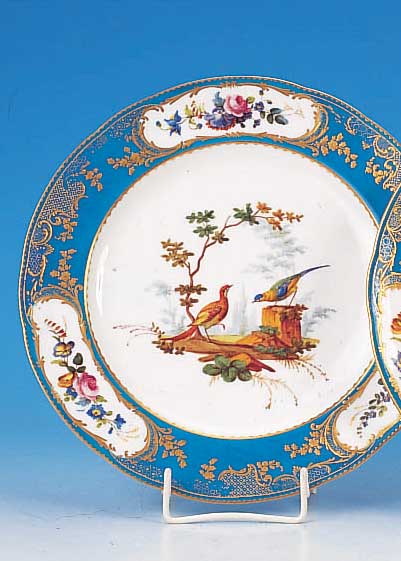 Teller, Sèvres, um 1780/90, Weichporzellan, blauer Rand mit Golddekor und Blumenmalerei inKartuschen, mittig feine bunte Malerei von exotischen ...