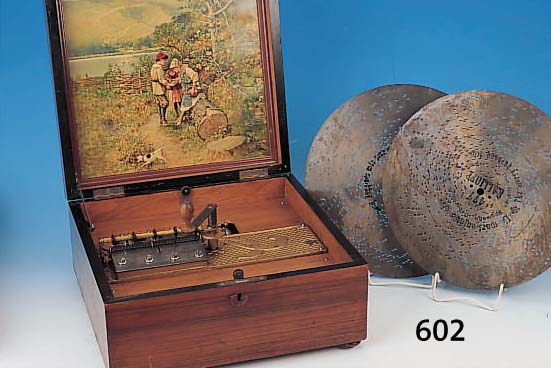 SPIELUHR KALLIOPE, DEUTSCH, UM 1910, NUßBAUMGEHäUSE MIT SCHRIFTZUG UND BANDINTAR- SIEN, INNENDECKEL MIT FARBLITHOGRAPHIE, VIER ...