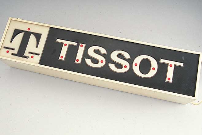 TISSOT WERBESCHILD, WOHL 70ER JAHRE, ELEK- TRIFIZIERT, NOCH ALTER STECKER OHNE ERDUNG, BELEUCHTBAR, FUNKTION NICHT GEPRüFT, M. CA. 12 X 63,5 X ...