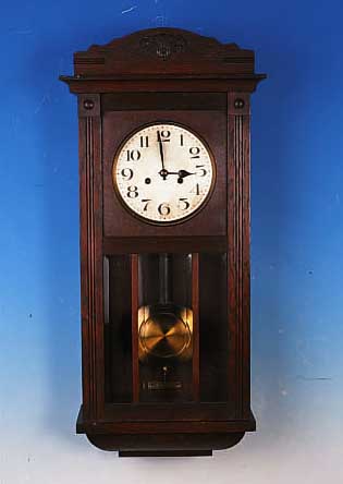 WANDUHR, DEUTSCH, 30ER JAHRE, EICHENHOLZ- GEHäUSE, SCHWUNGBEREICH DES PENDELS FACETTIERTVERGLAST, VERSILBERTES ZIFFERBLATT (ALTERS- BEDINGT ...