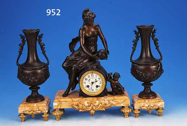 KAMINUHR MIT ZWEI BEISTELLERN, FRANKREICH, UM 1920, GEäDERTER MARMORSOCKEL, SPRITZGUßAP- PLIKEN, FIGURENBEKRöNUNG MIT SEITL. PUTTO, ...