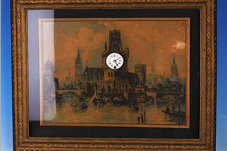 BILDERUHR MIT MUSIKSPIELWERK, DEUTSCH, UM 1880/1900, VERZIERTER VERGLASTER RAHMEN, PASSEPARTOUT, ÖLDRUCK, DARSTELLUND EINER STADTMIT FLUß, ...