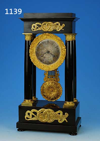FRüHE PORTALUHR, FRANKREICH, UM 1840/50, SCHWARZ GELACKTES HOLZGEHäUSE, IN STRENGER SYMETRIE, KAPITELLE-BASEN- UND PHLINTEN VER- GOLDET, ...