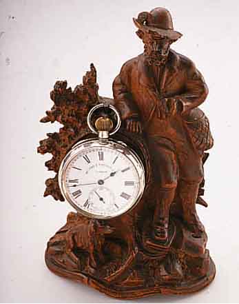 UHRENSTäNDER JäGER MIT HUND IN LANDSCHAFT, HOLZSCHNITZEREI, 2. HäLFTE 19. JAHRH., TEILW. BESCH., H. CA. 18 CM, M. TASCHENUHR, SIGN. MC CABE & ...