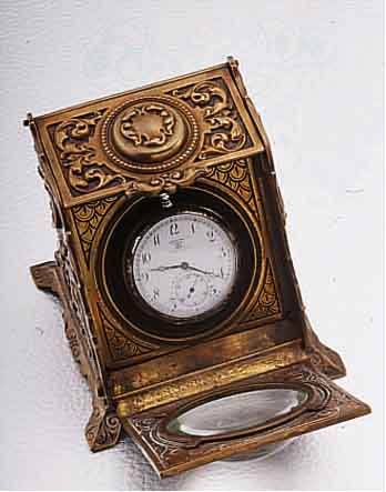 UHRENSTäNDER IN FORM EINER KOHLENSCHüTTE, MESSINGGUß, UM 1895, AUFKLAPPB., UHR M. HAL- TERUNG AUSSCHIEBB., LUPENVORSATZ, MAßE CA. 80 X 80 ...