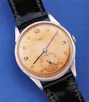 EBEL HERRENARMBANDUHR, SCHWEIZ UM 1940, METALL NACHVERCHR., EDELST.-BODEN U. GLASR. GEDR., KUPFERFARB. BLATT FL., ORIG. GEBL. STAHLZEIGER, ...