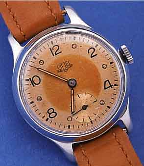 GUB HERRENARMBANDUHR, DEUTSCHLAND UM 1955, METALLGEH. VERCHR., BER., EDELST.-BODEN U. GLASR. GEDR., ORIG.-BLATT FL., KAL. 60, 15 ST.HANDAUFZUG, ...