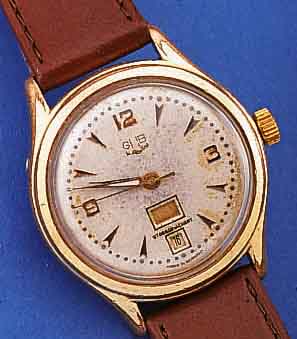 GUB HERRENARMBANDUHR, KAL. 66,1, UM 1959, TAG U. DATUM (SCHNELLKORREKTUR), METALL VERG.,BER., INCABL. STOßGES., HANDAUFZUG, EZW 2, EZG 3