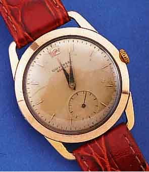 UNIVERSAL GENEVE HERRENARMBANDUHR, SCHWEIZ UM 1949, RG 750/000, BODEN U. GLASR. GEDR., ORIG.-BLATT ALTERSBED. FARBL. GET., LEDERB. NEU, 15 ST., ...