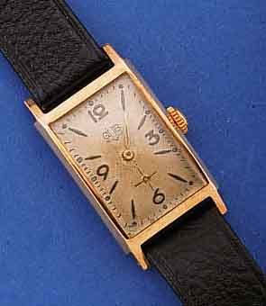 GUB HERRENARMBANDUHR, DEUTSCHLAND UM 1957, METALL ROSEVERG., EDELST.-BODEN GEDR., RECT.- FORM IN SICH GEW., ORIG.-BLATT VERS., ALTERS- BED. FL., ...