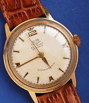 GUB HGUB HERRENARMBANDUHR AUTOMAT, KAL. 68,1, DEUTSCHLAND UM 1964, METALL ROSEVERG., BER., EDELST.-BODEN GESCHR., ORIG.-BLATT, ALTERSBED. FL., ...