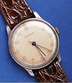 ETERNAETERNA HERRENARMBANDUHR, SCHWEIZ UM 1942, EDELST., BODEN U. GLASR. GEDR., BLATT ALTERS- BED. FL., AUßER NEUEM LEDERB. ORIG.-ZUST., ...