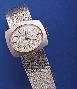 DUGENA DAMENGOLDBANDUHR, WG 585/000-GEH. INCL. WG-BAND RHOD., DEUTSCHLAND/SCHWEIZ UM 1970, BODEN GEDR., RUNDANKERW., 17 ST., HAND- AUFZUGKAL. ETA ...