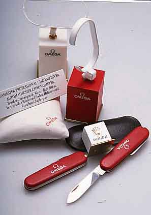 REICHHALTIGES KONVOLUT UHRENSTÄNDER U. WERBE- MATERIAL, BESTEHEND AUS 11 OMEGA UND 1 ROLEX UHRENSTÄNDER, 5 OMEGA TASCHENMESSERN IN SCHUTZHÜLLE ...