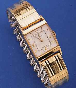 LE COULTRE HERRENARMBANDUHR, SCHWEIZ/USA UM 1950, GG-FILLED-GEH., RECT.-FORM, KONKAV-GL., ZEITIDENT. METALLBD. M. GG-AUFLAGE, TEILW. SCHERENGL., ...