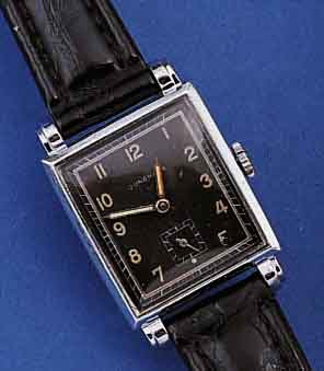 JUNGHANS HERRENARMBANDUHR, DEUTSCHLAND UM 1942, GR. RECT.-FORM, MAßE CA. 39 X 26 MM, METALL HARVERCHR., EDELST.-BOD. AUFGEDR., SCHWARZES ORIG. ...