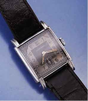 JUNGHANS HERRENARMBANDUHR, DEUTSCHLAND UM 1942, METALL VERN., BER., EDELST.-BODEN GEDR., SCHW. BLATT, ALTERSBED. FARBL. GET., 16 ST., RUNDANKERW., ...