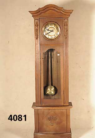 Standuhr, deutsch, um 1920, mittelbraunes EichefurniergehÄuse, Sichtglas des Pendels defekt, aufgesetzte Blatt- und Kelchschnitzer- ei, Kopfteil ...