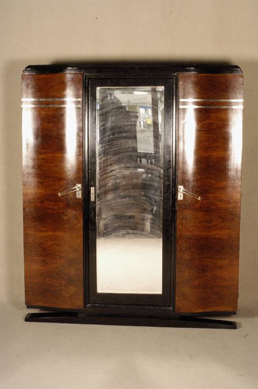 ArtDeco-Schrank, Frankreich, um 1920, kau- kasischer Nußbaum gespiegelt furniert, teil- weise schwarz abgesetzt, geschwungener Fuß, ausgefallene ...