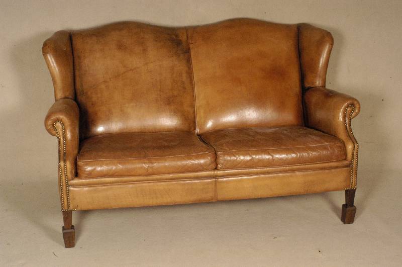 Ledersofa, deutsch, um 1950, seitlich in Ohrenform auslaufend, RÜcken vernagelt mit original MessingkÖpfen, eckige Beine, Leder mit alter ...