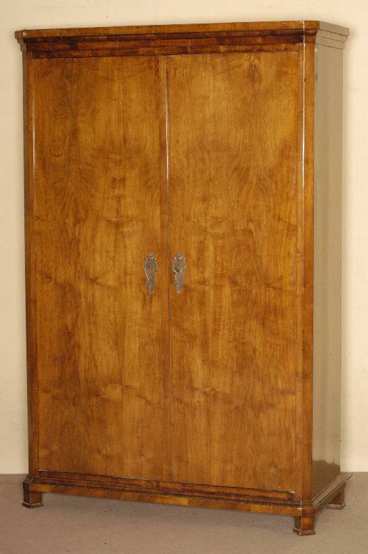 Biedermeierschrank, sÜddeutsch, um 1830/35, Korpus Weichholz, Nußbaumfurnier, z.T. gespiegelt verlegt, Kranz und Zarge 3- bzw. 4 -fach getreppt, ...