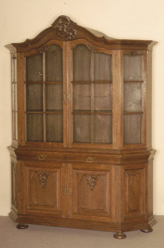 Prahlhans, deutsch, um 1910, Eiche massiv, z.T. furniert, seitliche und frontale Sprossenverglasung, gebogener Kopf mit plastischen Rocaillen- und ...