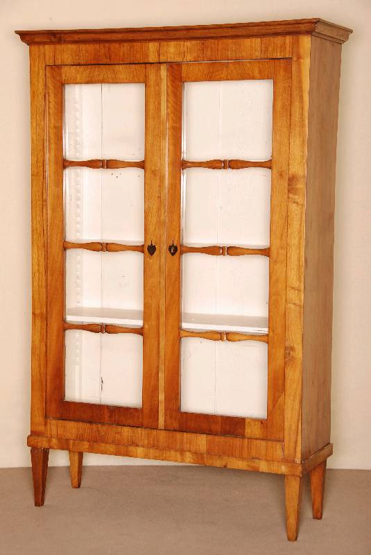 Biedermeiervitrine, deutsch, um 1820/30, Nußbaum, z.T. massiv, 2-tÜriger verglaster Korpus, auf Spitzbeinen, dezent geschnitzte Versprossung, ...