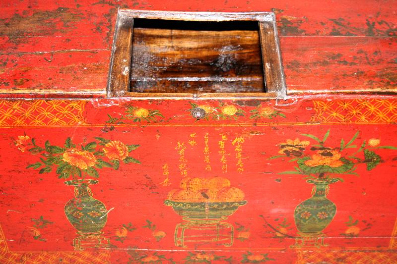 Detail a: Truhe, Mongolei, um 1900, Weichholz, rot gefaßt, FÜße schrÄg laufend, Front mit BlÜten und Vasen bemalt, mittig Obstschale, seitlich original ...