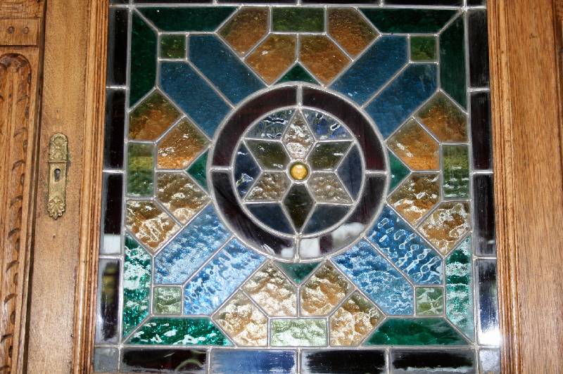 Detail a: Vielzweckschrank, Holland, um 1890/1900, Eiche massiv, 3-teilig, Oberteil verglast mit buntem Bleiglas, Lisenen mit Akanthusblättern, Maskaron und ...