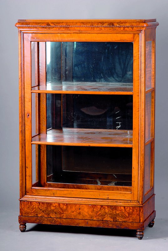 Glasvitrine, westdeutsch, um 1840, Nußbaumfurnier, Rückwand versp., z.T. besch., integr. Fußschublade, abgerundete Ecken, Zierfries, 3 Seiten ...