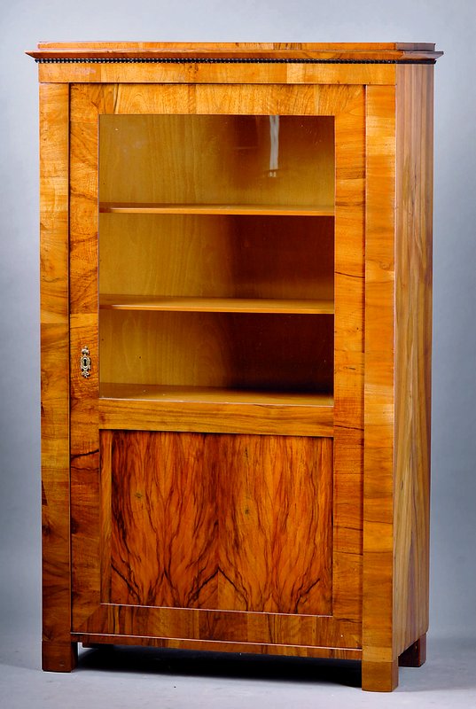 Vitrine, Biedermeier, um 1820, Nußbaumfurnier gesp. verlegt, 4 Einlegebretter, Front teilverglast, Kopf getreppt m. geschwärzter Leistenverz., l. ...