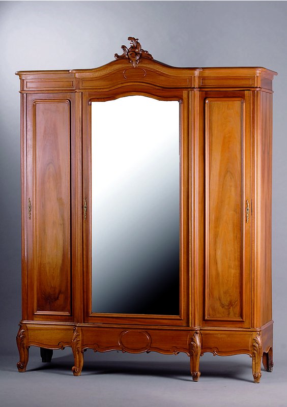 Schrank, Frankreich, um 1880-90, Nußbaum massiv und furniert, drei Türen, mittig facettierter Spiegeleinsatz, geschnitzte Bekrönung, Sockel mit ...