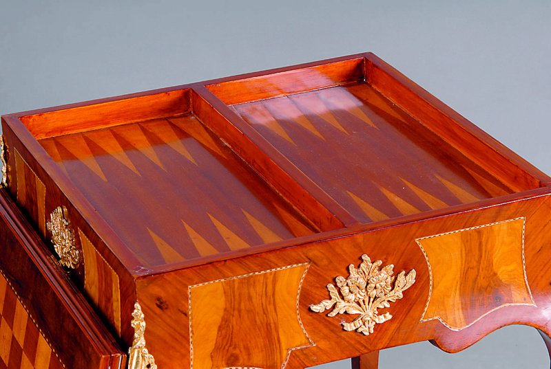 Detail c: Spieltisch, nach altem franz. Vorbild, Wurzelnußfurnier, vielfach gesp. verlegt, Beine und Zarge geschweift, reiche Bronzeappliken, Bandintarsien, ...