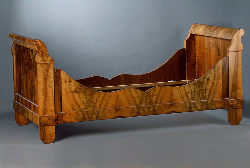 Bett, süddeutsch, um 1835/40, Wurzelnußfurnier, allseitig geschweift, angedeutede Volutenverz., Gebr.-Sp., ca. 98x217x108 cm. Liegefläche 90x200 cm