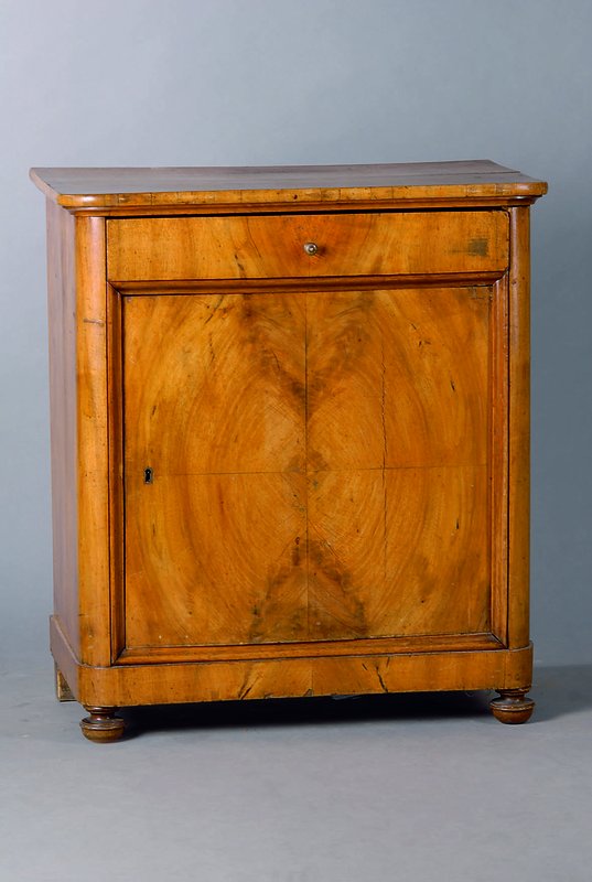 Kommode, deutsch, um 1830/40, 1 Tür 1 Schublade, abgerundete Ecken, Nußbaum, Furnierschäden, st. Gebr.-Sp., alt belassen, Tür in Rahmenfüllung, ...