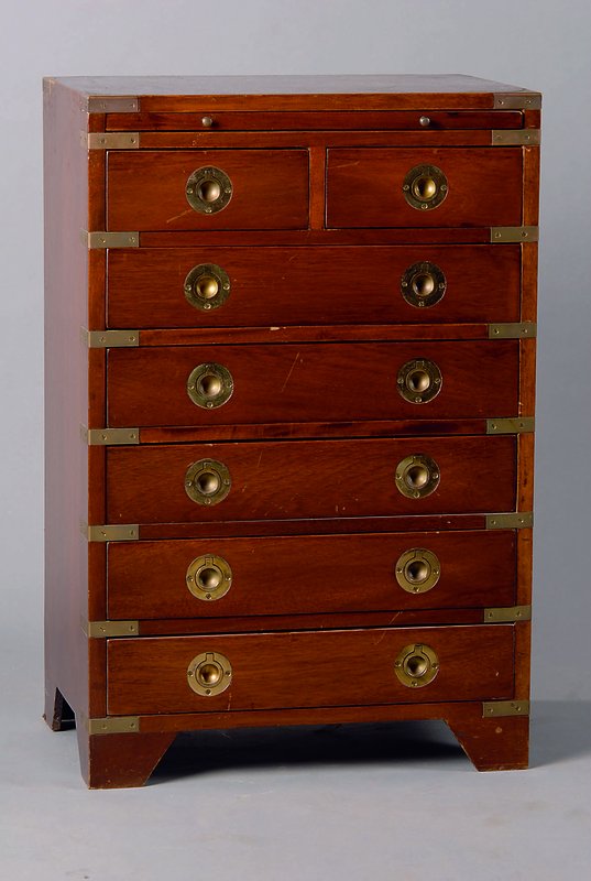 Schubladenschränkchen, Mitte 20. Jh., Mahagoni, Messingappliken, 7-schübig, 1 Ausziehbrett, st. Gebr.-Sp., ca. 70x46x30 cm