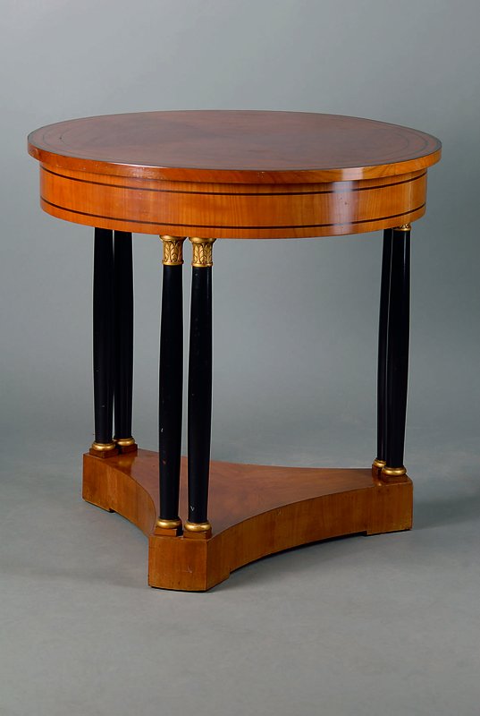 Runder Tisch, wohl Stuttgart, um 1905/10, Kirschbaum, feistehende Säulen geschwärzt, teilsgoldfarbene Abschlüsse, schwarz intarsiert, Polsterung ...
