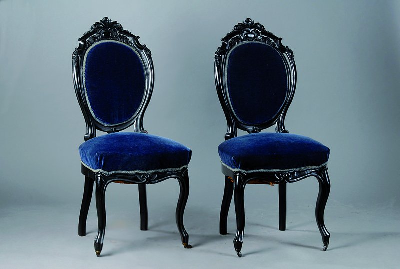 6 Stühle, deutsch, um 1835/40, schwarz gefasst, allseitig geschweift u. gerieft, Lehne m. reicher Blüten und Akanthusblattschnitzerei, blauer Bezug ...